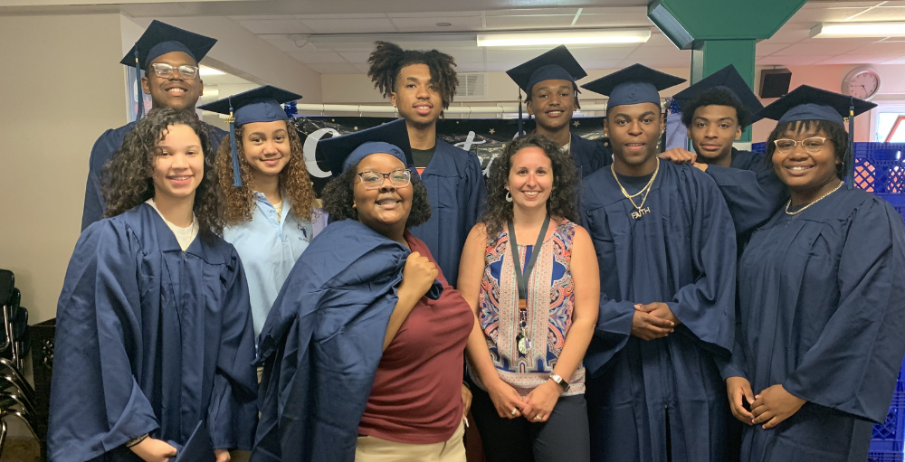 Syracuse Academy of Science high school’s Class of 2022 poses with their third-grade teacher, Syracuse Academy of Science elementary school’s Dean of Elementary, Meghan Miller.